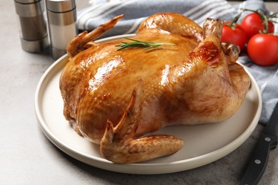 Photo of Tasty roasted chicken with rosemary on light grey table