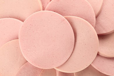 Photo of Slices of tasty boiled sausage as background, top view