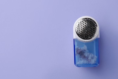 Fabric shaver with fuzz on lilac background, top view. Space for text