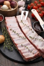 Photo of Fresh raw pork ribs with thyme on wooden table