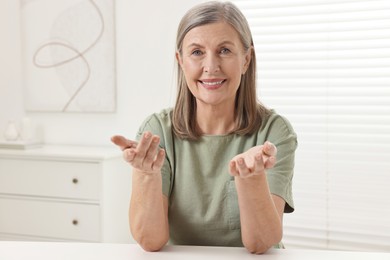 Photo of Happy woman at white table in room