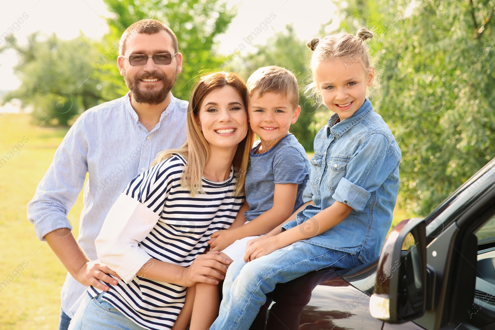 Photo of Happy family with children near car outdoors. Taking trip together