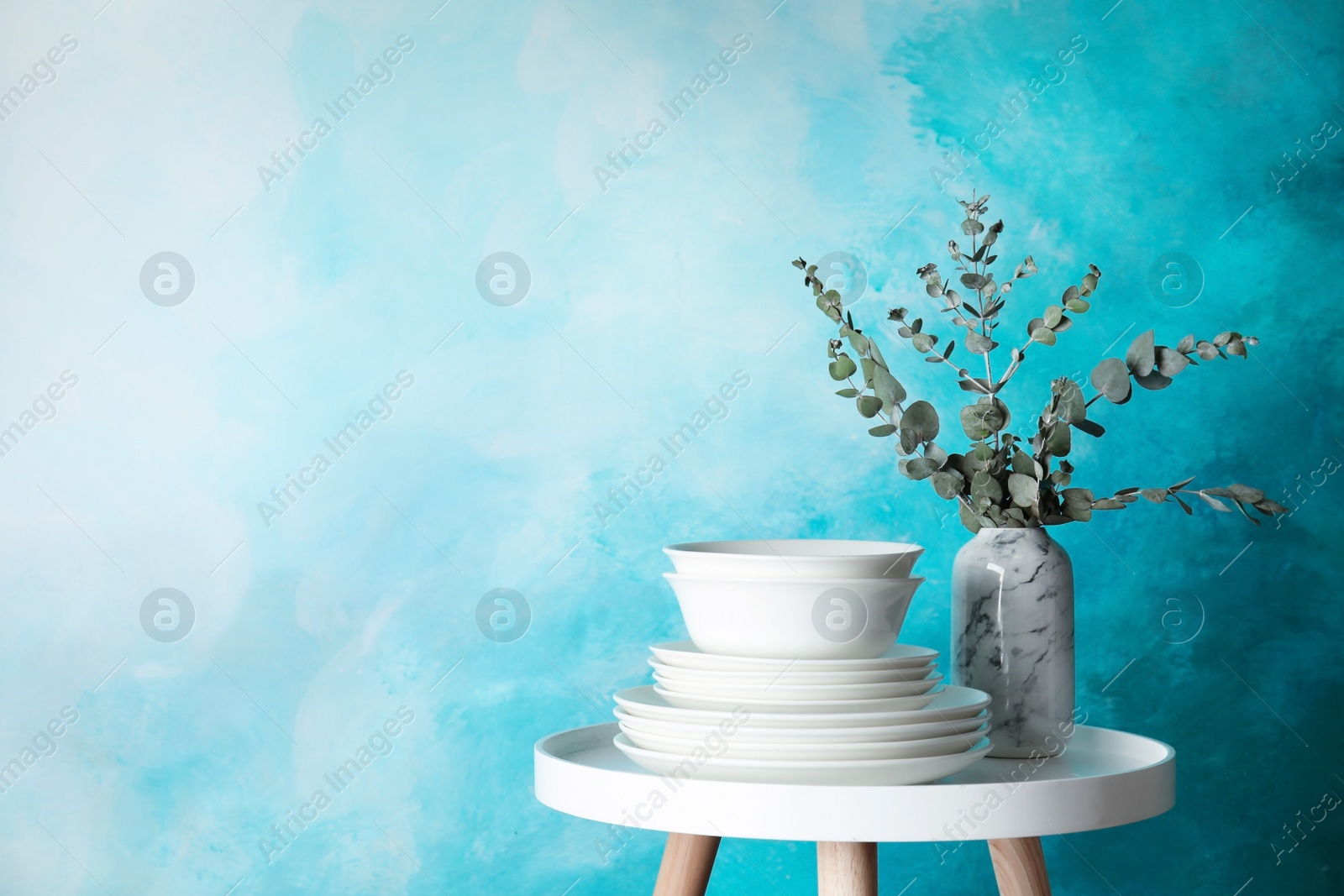 Photo of Composition with dinnerware on table against color background, space for text. Interior element