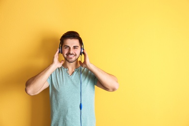 Handsome man with headphones enjoying music on color background. Space for text