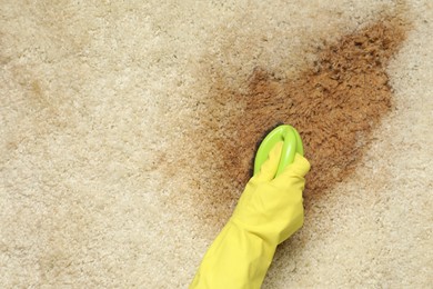 Photo of Woman removing stain from beige carpet, top view. Space for text