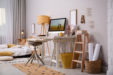 Photo of Comfortable workplace with modern computer near light wall in bedroom. Interior design