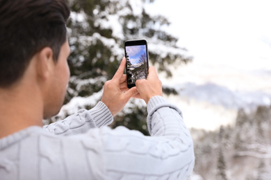 Photo of Man taking picture of snowy tree outdoors