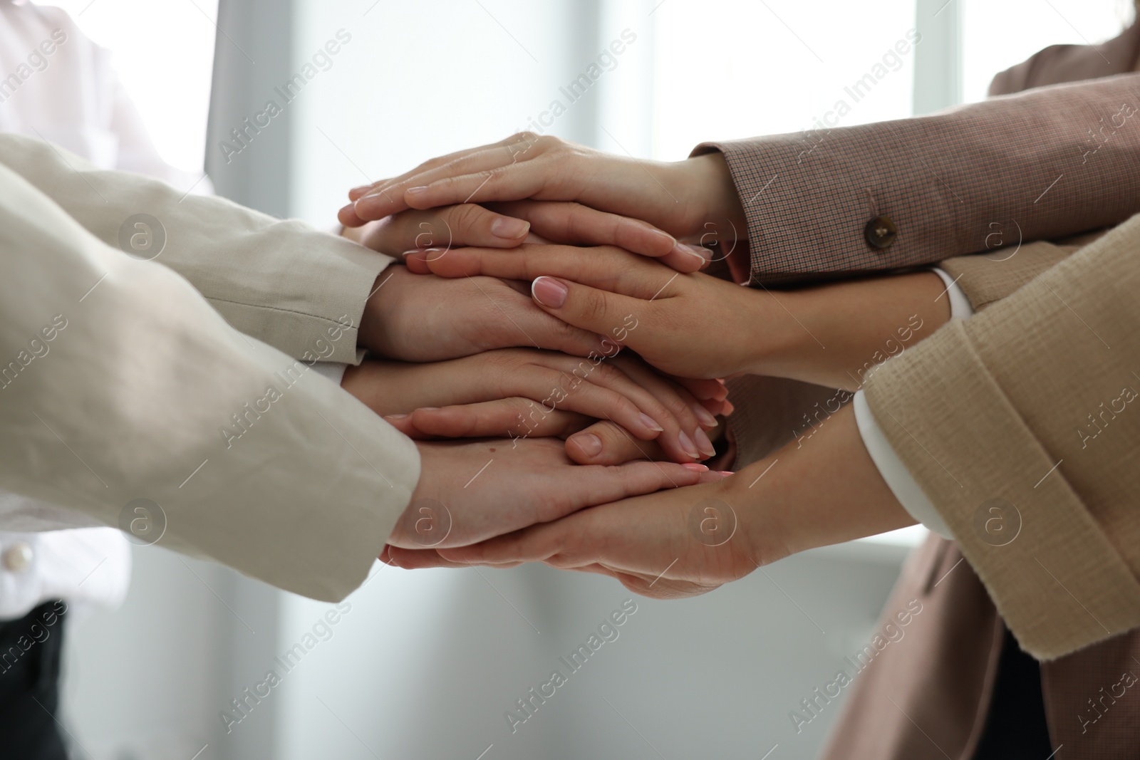 Photo of Group of people holding hands together indoors, closeup. Unity concept