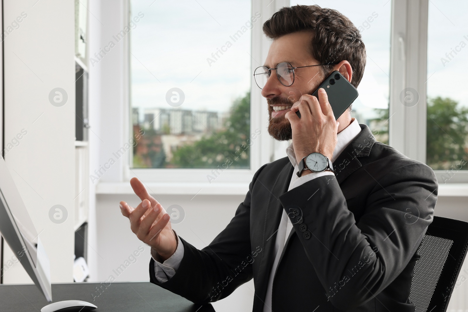 Photo of Handsome businessman talking on smartphone at workplace in office