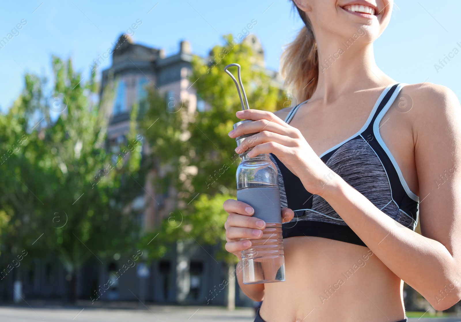 Photo of Young woman holding bottle with clean water on street. Space for text