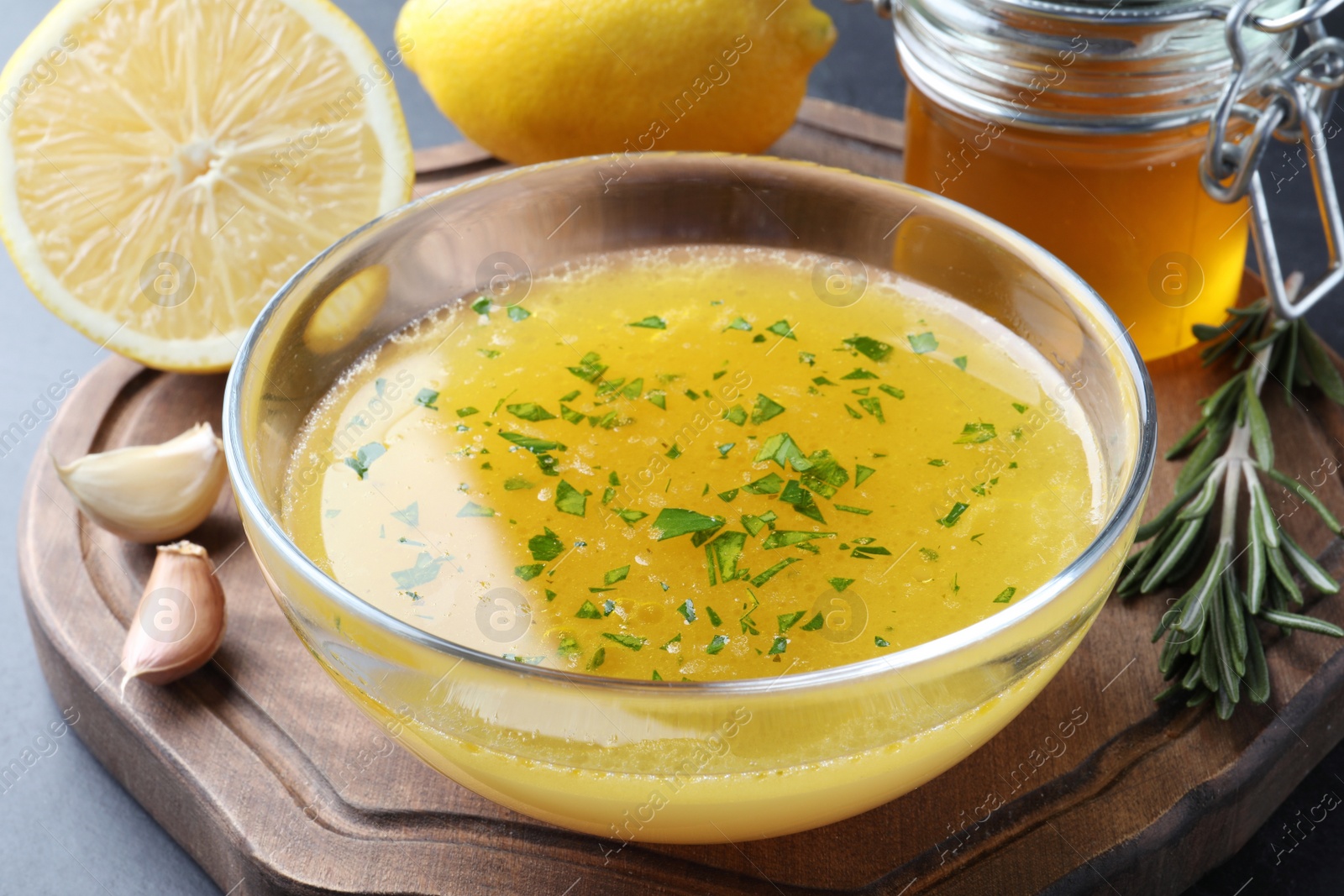 Photo of Bowl with lemon sauce and ingredients on table, closeup. Delicious salad dressing