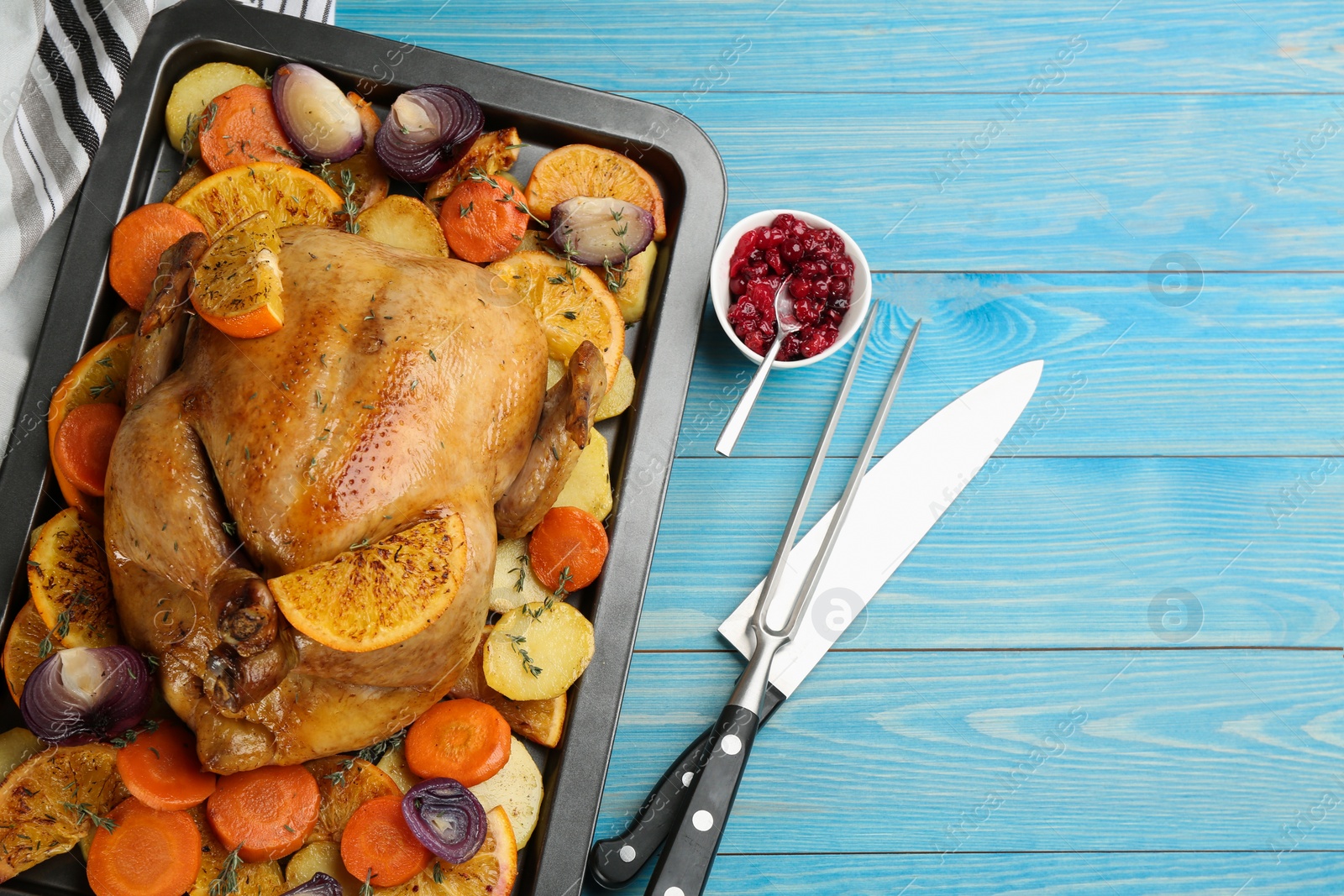 Photo of Delicious chicken with oranges and vegetables on light blue wooden table, flat lay