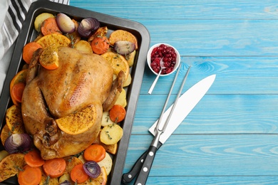 Delicious chicken with oranges and vegetables on light blue wooden table, flat lay