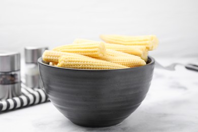 Bowl of pickled baby corn on white marble table, closeup