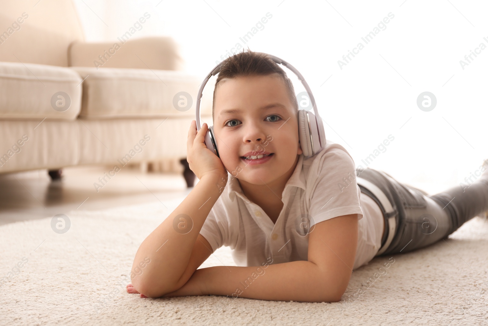 Photo of Little boy listening to music on floor at home