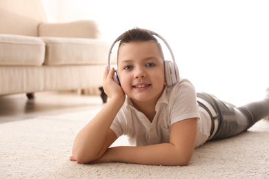 Photo of Little boy listening to music on floor at home