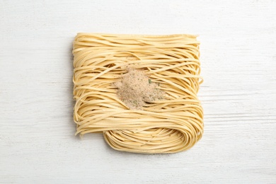 Photo of Block of quick cooking noodles with spices on wooden background, top view