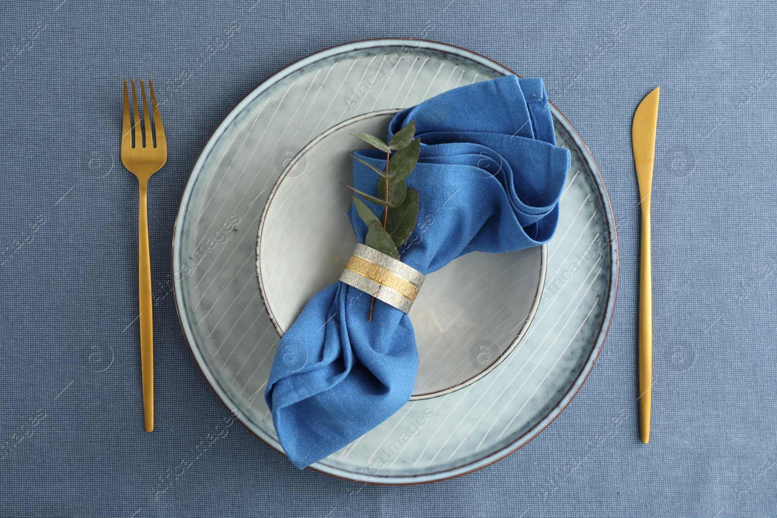 Photo of Stylish setting with cutlery, dishes, napkin and floral decor on table, top view