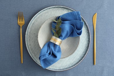 Stylish setting with cutlery, dishes, napkin and floral decor on table, top view