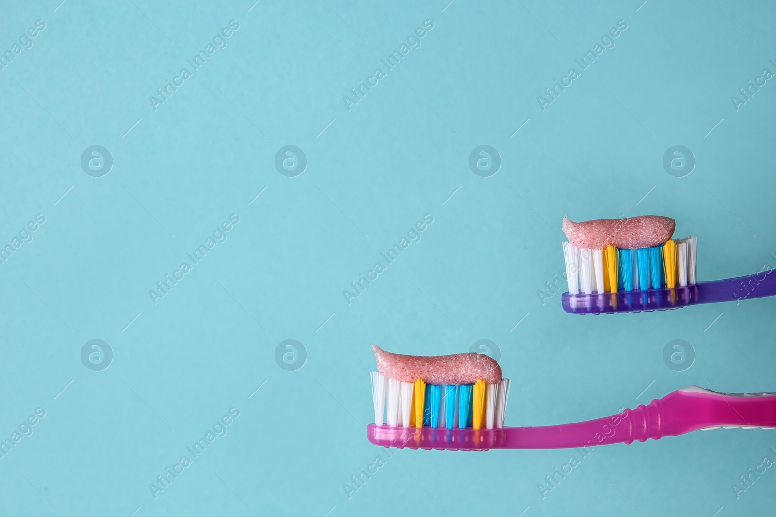 Photo of Toothbrushes with paste on color background, closeup