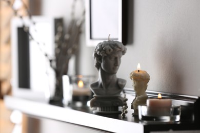 Photo of Beautiful David bust candles on table indoors