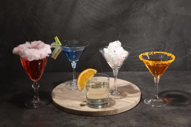 Tasty cotton candy cocktail and other alcoholic drinks in glasses on gray textured table