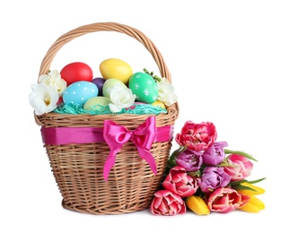 Wicker basket with bright painted Easter eggs and spring flowers on white background