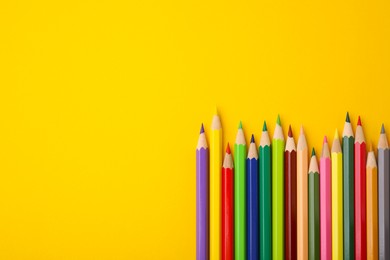 Photo of Colorful wooden pencils on yellow background, flat lay. Space for text