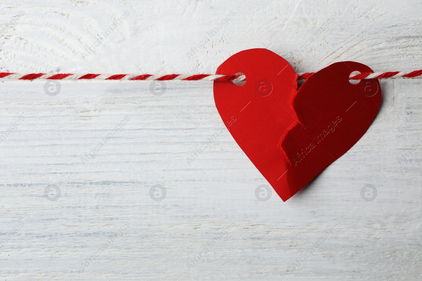 Photo of Broken red paper heart and rope on white wooden background. Relationship problems concept