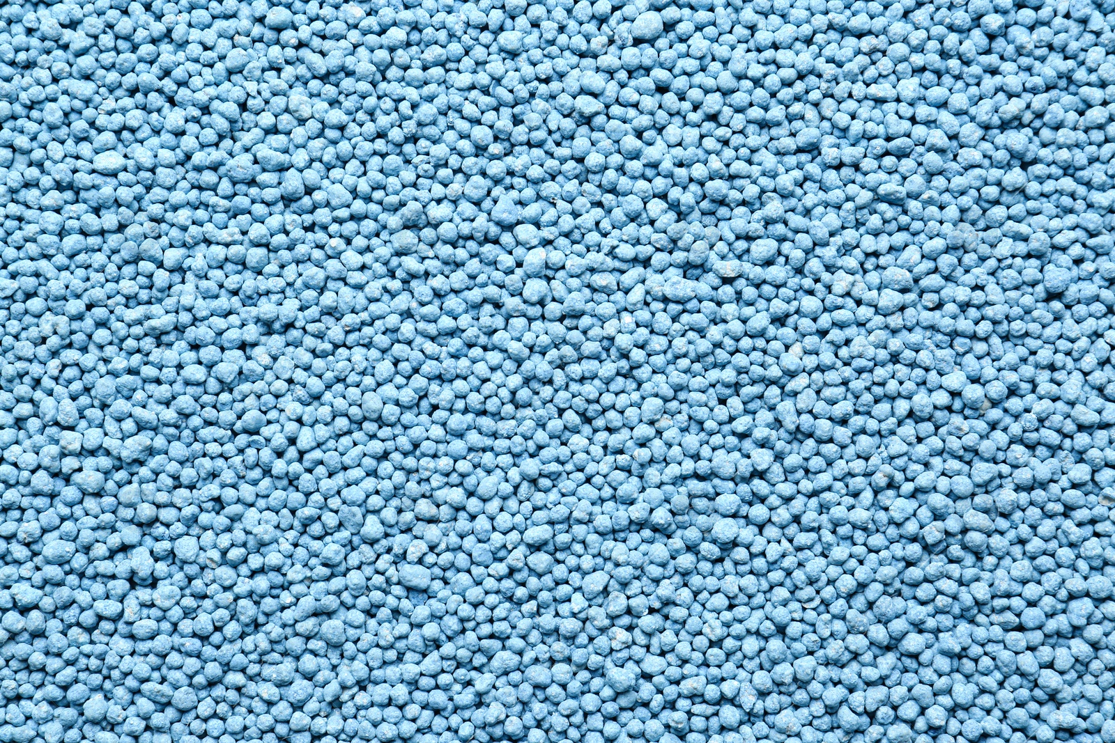 Photo of Blue granular mineral fertilizer as background, top view