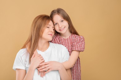 Photo of Portrait of happy mother and her cute daughter on beige background. Space for text