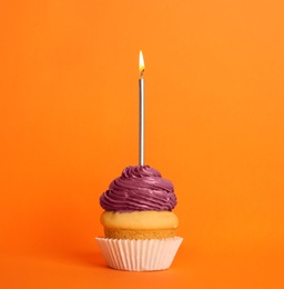 Birthday cupcake with candle on orange background