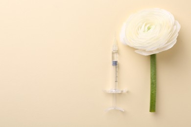 Photo of Cosmetology. Medical syringe and ranunculus flower on yellow background, flat lay. Space for text