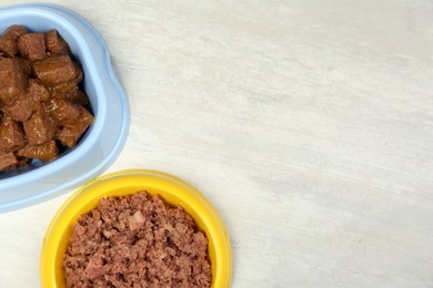 Photo of Different pet food in feeding bowls on white table, flat lay. Space for text