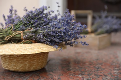 Photo of Beautiful lavender flowers and straw hat on marble tiles outdoors