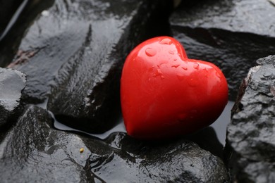 Photo of Red decorative heart on stones and water, closeup. Space for text