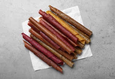 Delicious fruit leather rolls on grey table, flat lay