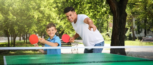 Image of Man with his son playing ping pong in park. Banner design