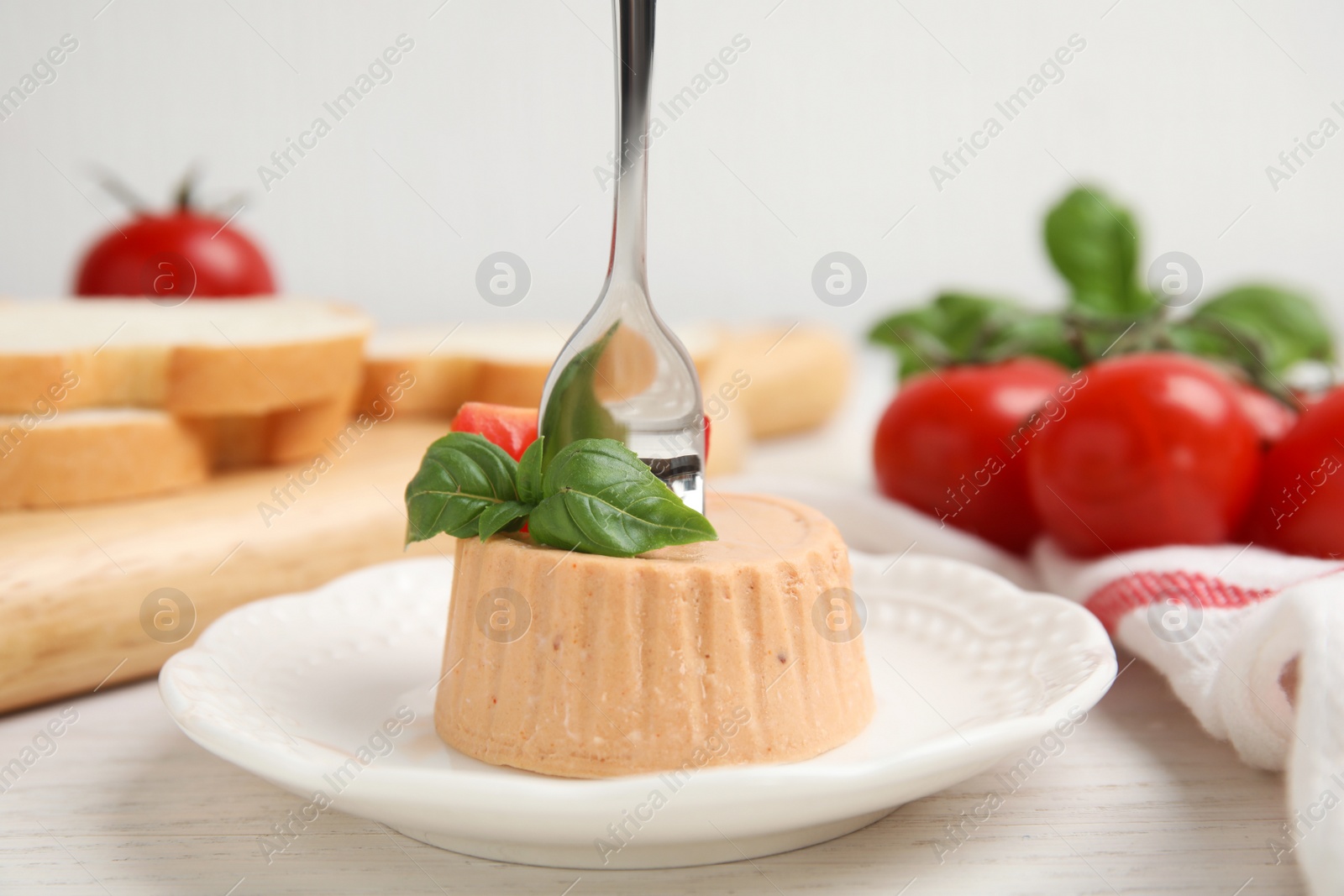 Photo of Delicious meat pate with basil and tomato served on white wooden table