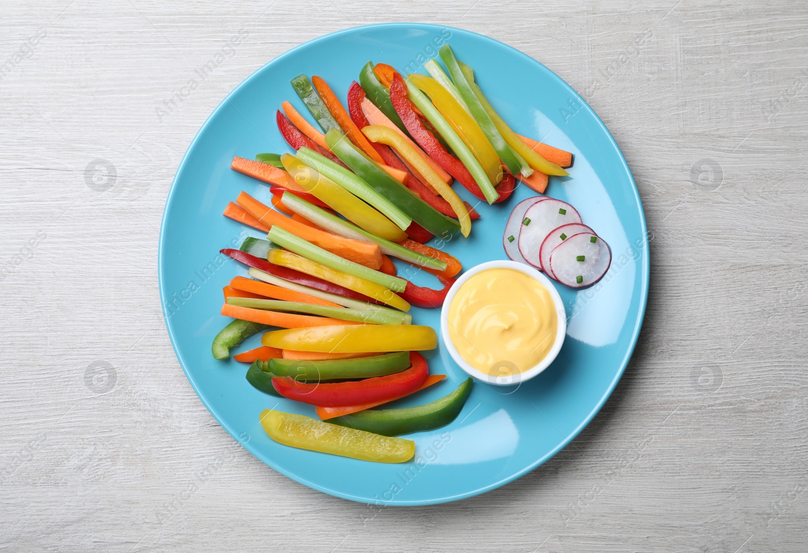 Photo of Different vegetables cut in sticks and dip sauce on light wooden table, top view