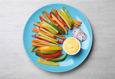 Photo of Different vegetables cut in sticks and dip sauce on light wooden table, top view