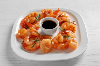 Photo of Plate with delicious fried shrimps and sauce on wooden background