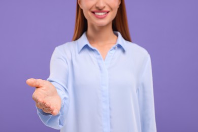 Photo of Woman welcoming and offering handshake on violet background, closeup