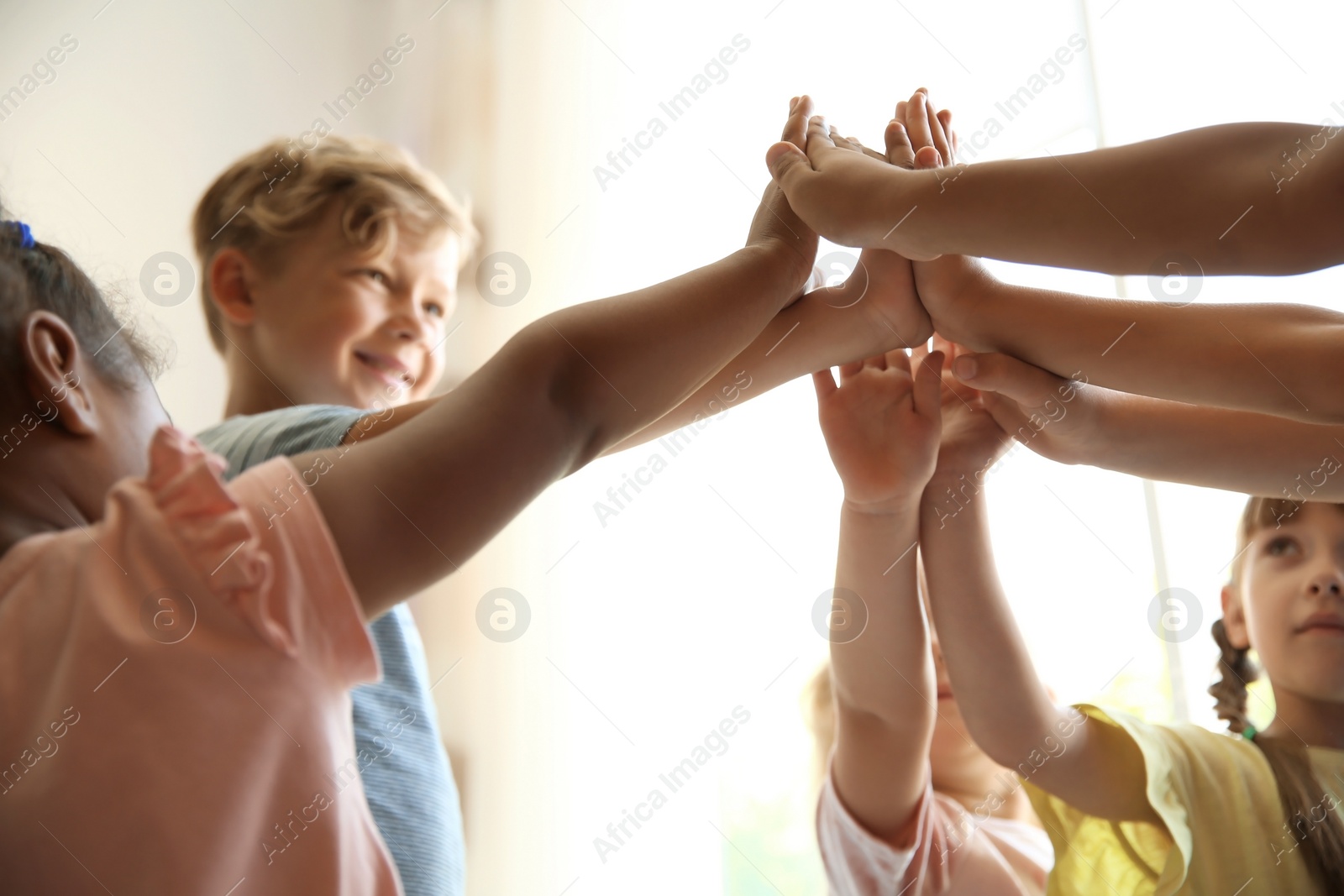 Photo of Little children putting their hands together on light background. Unity concept