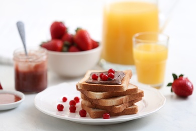 Toasted bread with chocolate spread and cranberries on white table in kitchen