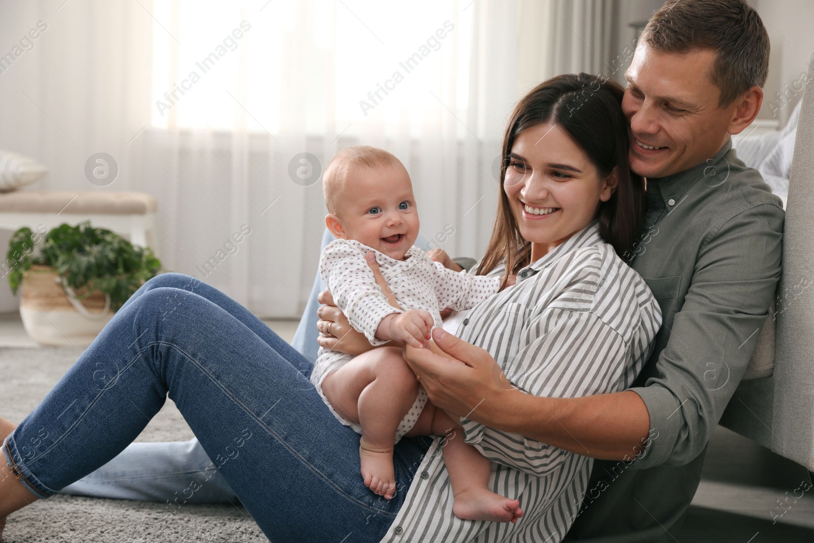 Photo of Happy family with their cute baby on floor in living room