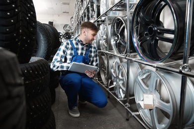 Young male mechanic with tablet computer in automobile service center