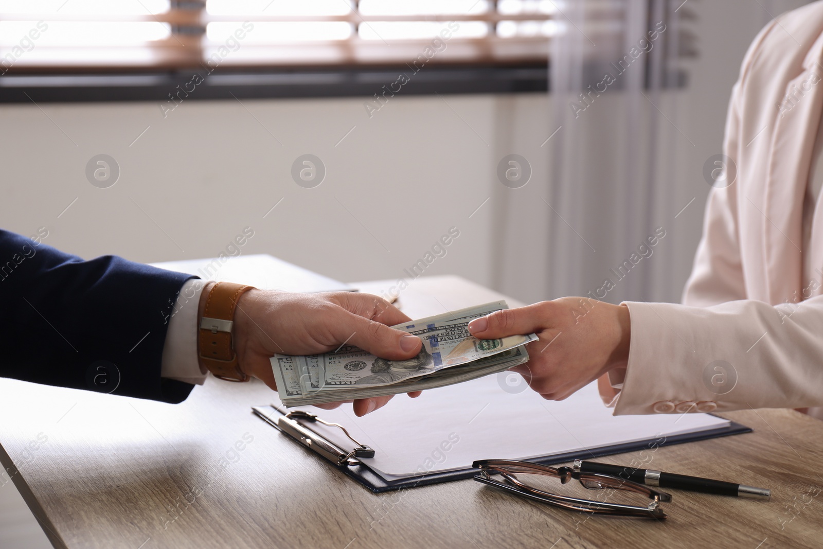 Photo of Man giving bribe to woman at table in office, closeup