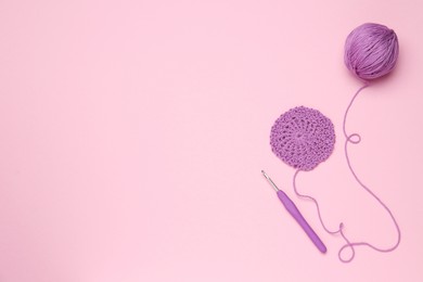 Knitting and crochet hook on pink background, flat lay. Space for text