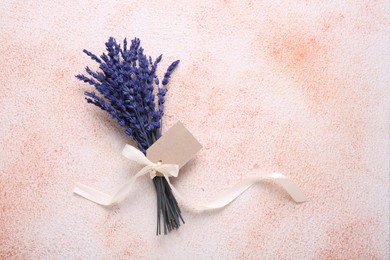 Photo of Bouquet of beautiful preserved lavender flowers with blank tag and ribbon on color textured table, top view. Space for text